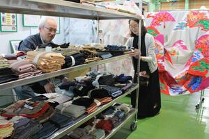 創明工芸が工場内に設けた販売店で、着物のリメーク用の生地を確認する澁木恒利さん(左奥)と奈美さん=燕市小池