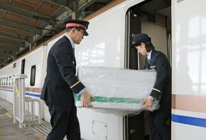 錦鯉の入った箱が、新幹線へ慎重に積み込まれた=3月20日、長岡市城内町2のJR長岡駅