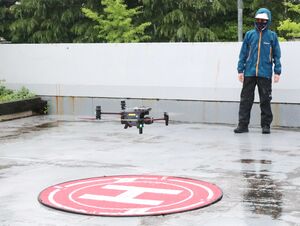 島田技建の担当者によるドローンの飛行実演。雨天の中、難なく飛行し、関係者が災害時の応援業務を期待した=三条市旭町2