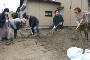 通りにあふれ出た土砂を協力して集める住民たち=1月3日、新潟市西区善久