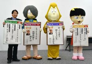 「第20回妖怪川柳コンテスト」の入賞作を発表する関係者と着ぐるみの鬼太郎ら=19日午前、鳥取県境港市
