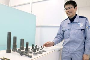 JFE精密が冷間鍛造で製造する自動車部品について説明する山崎伸次社長=新潟市東区
