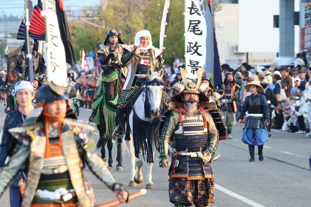 １００回目の謙信公祭で上杉謙信役を務め、沿道の観客に笑顔で手を振る松平健さん＝２３日、上越市