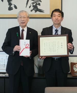 新発田市に100万円を寄付した北興化学工業新潟工場の秋山正樹工場長(右)=新発田市役所