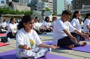 「国際ヨガの日」に開かれたイベントでヨガをする子どもら=21日午前、東京都中央区の築地本願寺