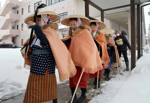 大雪の中、瞽女の格好をして雁木の下を歩きながら「門付け」を再現した一行=2月8日、上越市高田地区