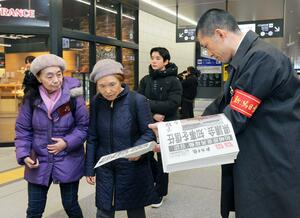 新潟日報号外を受け取る人たち＝２２日、新潟市中央区のＪＲ新潟駅