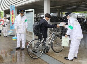 自転車利用者に鍵やチラシが入った袋を渡し、鍵かけの徹底を呼びかける新潟西署員=新潟市西区のJR内野駅前