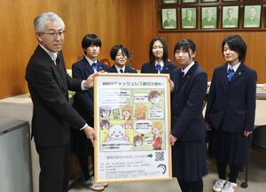 西田誠・村上税務署長(左)に制作したポスターを手渡す芸術・文芸部漫画研究班の生徒たち=村上市田端町