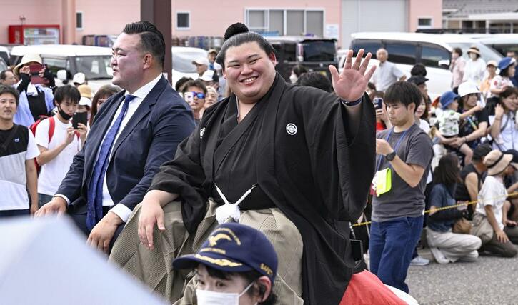 石川県津幡町で行われた大相撲の横綱昇進を祝うパレードで、沿道に集まった人たちの声援に応える大の里関。左は二所ノ関親方＝２９日午後