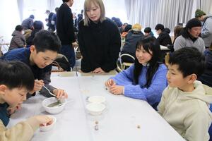 大河津分水の砂を小瓶に詰めるワークショップを楽しむ参加者ら=燕市五千石