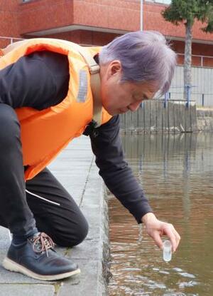 　池でミドリムシを探す芝上基成さん＝３月、茨城県つくば市