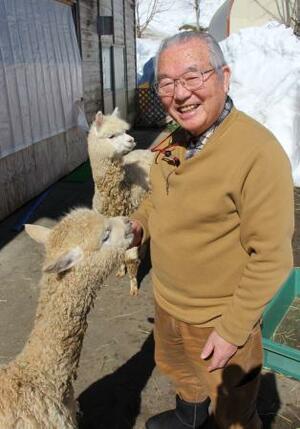 　じゃれつくアルパカに笑顔の青木勝さん＝新潟県長岡市