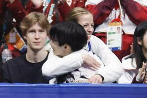 団体男子SPの演技を終え、鍵山優真を抱きしめるカロリナ・コストナー・コーチ(奥)=7日、ミラノ(共同)