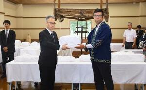 国交省の担当者からアイヌの遺骨を受け取る、「インカルシペの会」の安ケ平拓也さん(手前右)=14日午前、北海道白老町