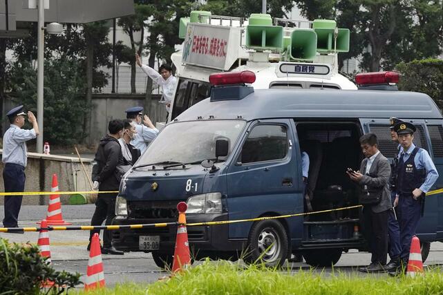 火炎瓶のようなものが投げ込まれた自民党本部付近。警察車両の前部が変色していた。後方は党本部から出る街宣車＝１０月１９日午前８時、東京・永田町