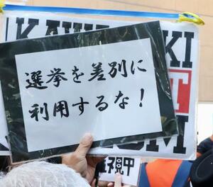 参院選候補者の街頭演説に対し、抗議のメッセージを掲げる人=12日、川崎市
