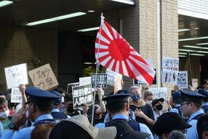 東京都議選の街頭宣伝で旭日旗を振る支持者と、「差別をやめろ」と声をからしプラカードを掲げて抗議する人たち=6月15日午後、東京都杉並区のJR高円寺駅前