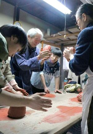 作家の説明を受け、無名異焼について学ぶ大学生ら＝佐渡市相川下京町