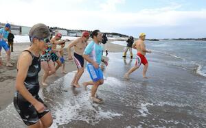 寒さの中、冬の日本海に駆け出す参加者たち=3日、新潟市中央区