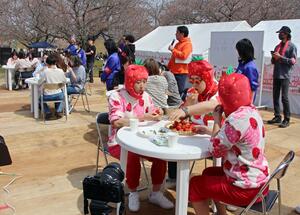 加治川桜・越後の姫まつりで、越後姫の早食いに挑戦する参加者=4月7日、新発田市真野原