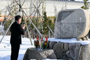 　慰霊碑に手を合わせる三幸製菓の牛腸栄一社長＝１０日午前、新潟県村上市