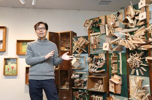 企画展の会場で作品について解説する丹治嘉彦さん＝新潟市中央区