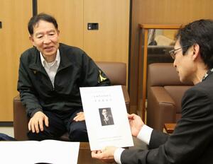 小山作之助生誕160周年の記念誌作成に取材協力した郷土史研究家の川上達也さん(左)=上越市大潟区土底浜
