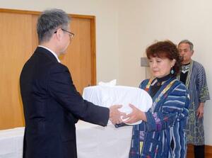 遺骨を受け取る釧路アイヌ協会の桃井芳子会長(右)=30日午前、北海道釧路市