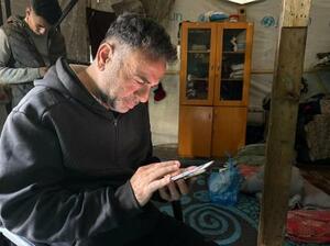 死亡した次男アメルさんの写真を見るマフムードさん＝２月２２日、ガザ中部デールバラハ（共同）