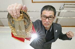 「モスクワオリンピック候補」と刻まれたベルトを掲げる木庭浩一さん=2020年、熊本市