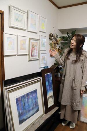 展示作を自宅で確認する高島詠子さん。花や猫などのほか、原発事故を二度と繰り返さないでと祈りを込めた絵もある＝新潟市中央区