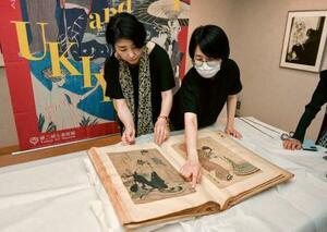 竹久夢二が収集した浮世絵のスクラップブック。左は「夢二郷土美術館」の小嶋ひろみ館長代理=23日、岡山市