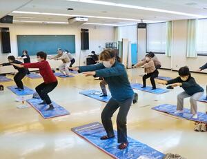 腰痛の予防に効くスクワットをする参加者=柏崎市栄町