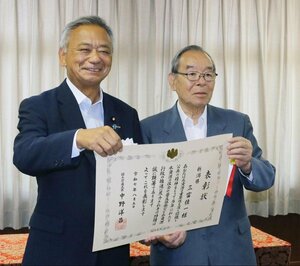 高橋克法国土交通副大臣(左)から水資源功績者表彰を受け取った三富佳一氏=5日、東京・霞が関