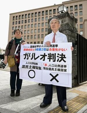 衆院選「1票の格差」訴訟の判決を受け、仙台高裁前で「ガリレオ判決」などと書かれた紙を掲げる原告側の升永英俊弁護士(右)ら=9日午後