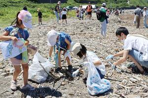 海岸のごみを拾い集める家族連れら=6月29日、上越市名立区