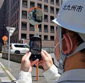 点検のためカーブミラーの写真を撮影する北九州市職員=7月、北九州市