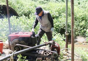田んぼに水を送るため、川から水をくみ上げる大橋伊勢治さん=柏崎市高柳町石黒