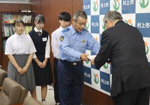 高橋邦芳・村上市長(右)に自転車ヘルメット着用に向けた支援などを盛り込んだ要望書を手渡す阿部博・村上署長=村上市役所
