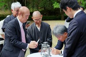 　「平和の塔」から移された原爆の残り火を手にする佐々木雅弘さん（左）＝２０日午前、福岡県八女市