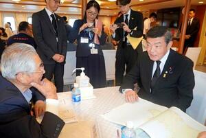 「洋上慰霊」の船内で、北方領土の元島民と交流する伊東沖縄北方相(右)=7日午前、北海道根室市の根室港沖