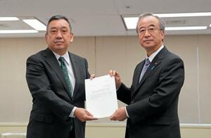 　原子力規制庁の金子修一長官（左）に確認を依頼する文書を手渡す新潟県の花角英世知事＝２３日午前、東京都港区