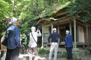 五合庵で解説を聞く新潟良寛研究会のメンバー=燕市国上