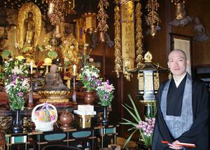 光琳寺本尊の阿弥陀如来像の前に立つ井上広法住職=1月、宇都宮市