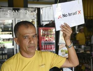 イスラエル人入店拒否の紙を掲げるポップさん=2025年12月、タイ・パンガン島(共同)