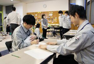 赤ちゃんの人形を抱いたまま書類を記入する体験に臨んだ市職員=阿賀野市岡山町