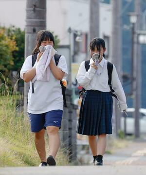 小型扇風機を手に兵庫県丹波市柏原町地区を歩く人たち。国内最高気温を更新した=30日午後