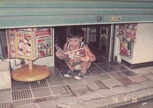 伊野尾書店の店頭で本を読む幼い頃の伊野尾宏之さん(提供写真)