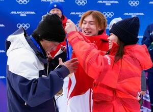 スノーボード女子スロープスタイルで優勝した深田茉莉(右)から金メダルをかけてもらう佐藤康弘コーチ。中央は練習仲間で五輪王者の蘇翊鳴=18日、イタリア・リビーニョ(共同)